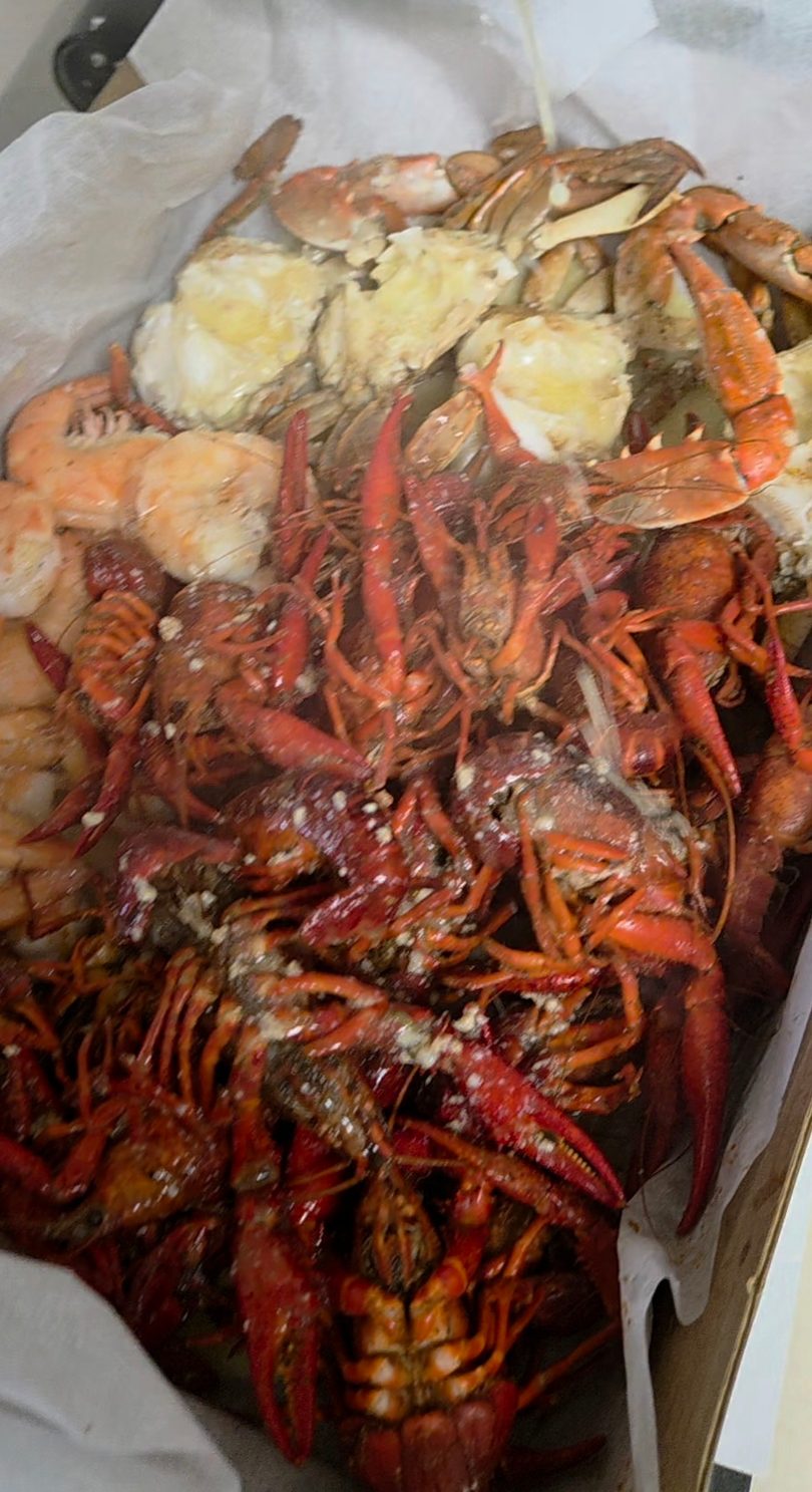 A seafood boil with crawfish, shrimp, and crab legs, seasoned with garlic and spices.